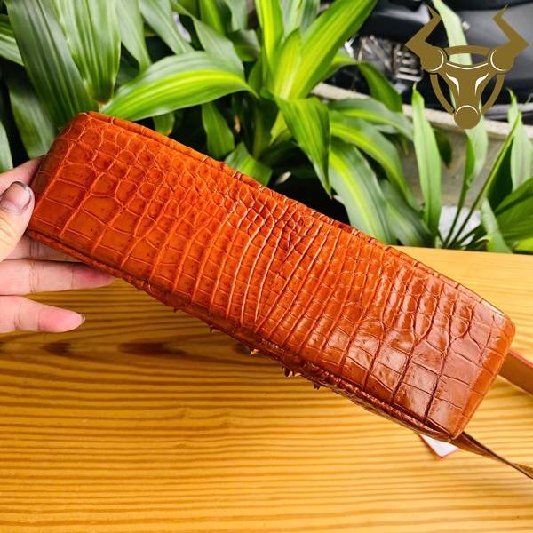 Túi đeo chéo nam da cá sấu gù màu vàng cam với ngăn chứa rộng.
